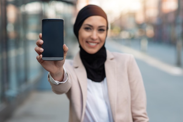 Mujer de negocios árabe con teléfono centrado en el teléfono
