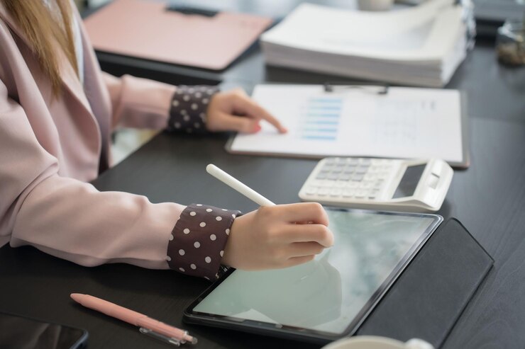 Foto una mujer de negocios asiática escribe en una tableta digital en su escritorio en una oficina moderna.