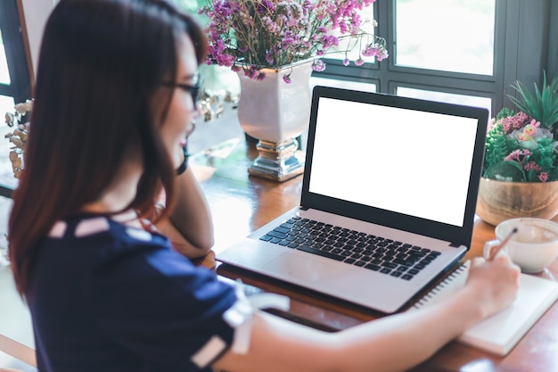 Mujer de negocios asiática espera recoger Smartphone hacer una nota y trabajar con la computadora portátil