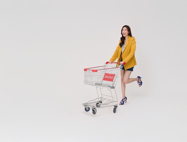 Mujer de negocios asiática feliz y emocionada empujando un carro de compras vacío o un carrito de compras