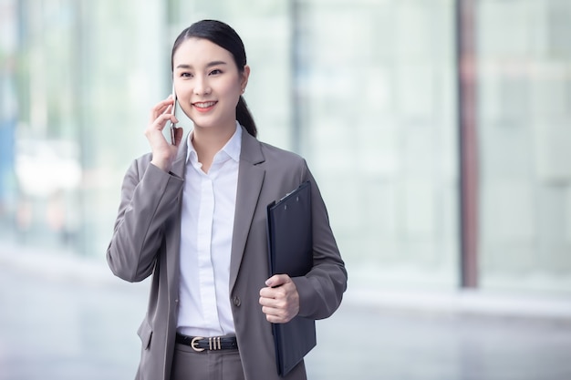 Mujer de negocios asiática feliz hablando por teléfono móvil