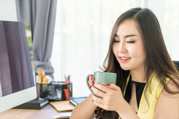 Mujer de negocios asiática feliz con taza de café