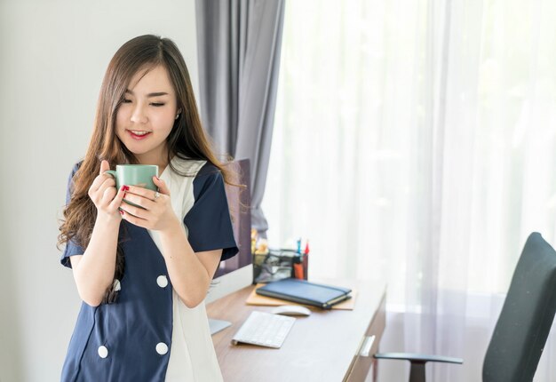 Mujer de negocios asiática feliz con taza de café