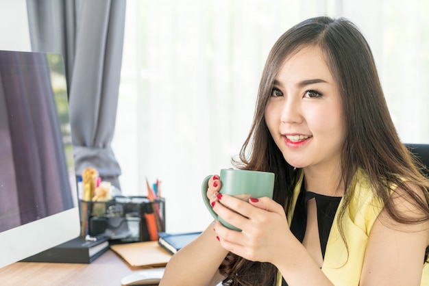 Mujer de negocios asiática feliz con taza de café