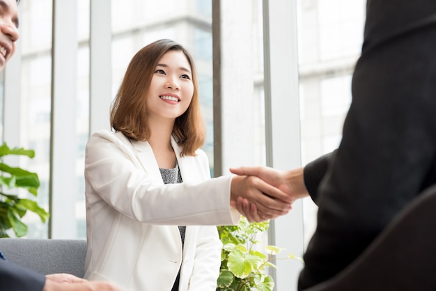 Mujer de negocios asiática haciendo apretón de manos con el cliente en el salón de la oficina