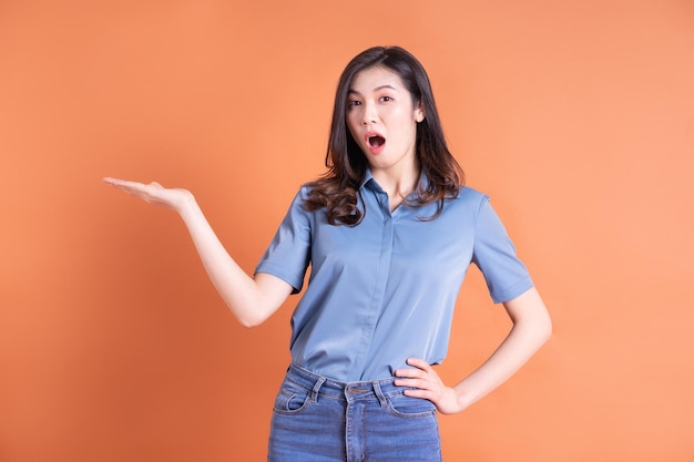 Mujer de negocios asiática joven posando sobre fondo naranja