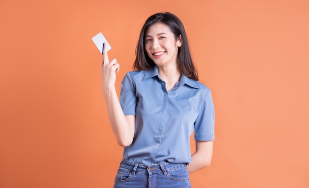 Mujer de negocios asiática joven posando sobre fondo naranja