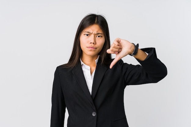 Mujer de negocios asiática joven que muestra un gesto de aversión, pulgares abajo. Concepto de desacuerdo