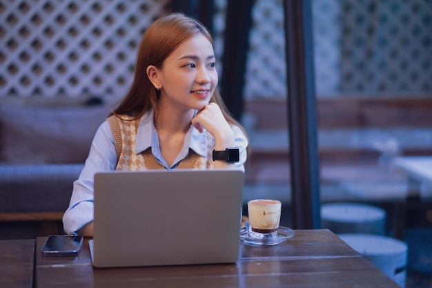 Mujer de negocios asiática joven que trabaja en la cafetería