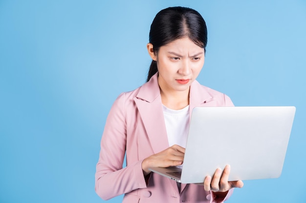 Mujer de negocios asiática joven que usa la computadora portátil en fondo