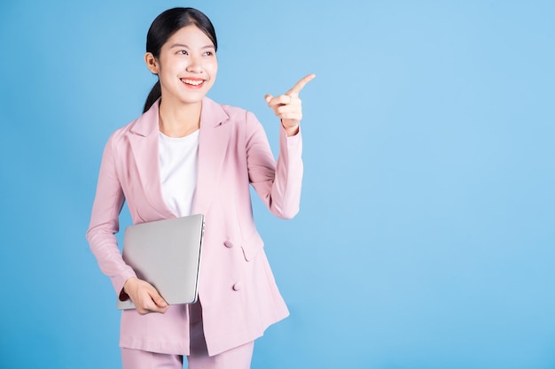 Mujer de negocios asiática joven que usa la computadora portátil en fondo