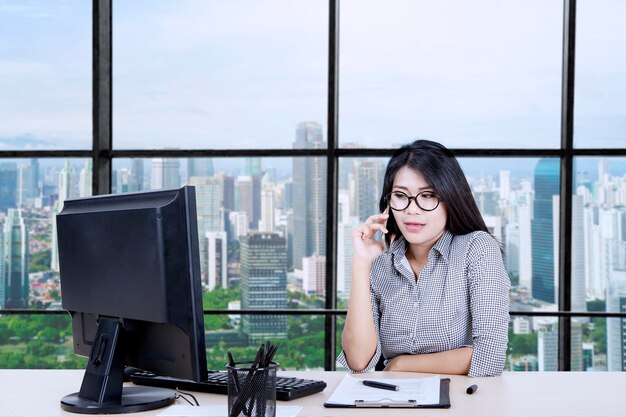 Mujer de negocios asiática llamando a alguien mientras trabaja
