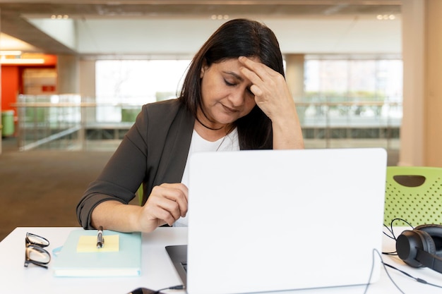 Mujer de negocios asiática madura con exceso de trabajo que se siente agotada después de un duro día de trabajo en la oficina