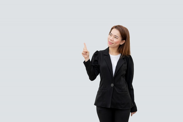 Mujer de negocios asiática que señala el dedo que presenta con el pelo largo en traje negro aislado en color blanco