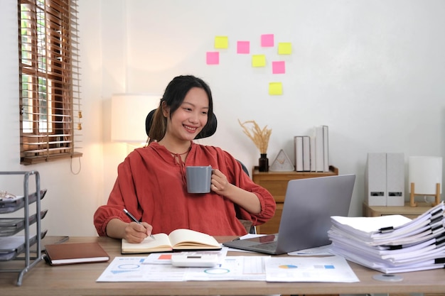 Mujer de negocios asiática que trabaja en una cafetería con trabajo de papel de computadora portátil Concepto de mujer de negocios