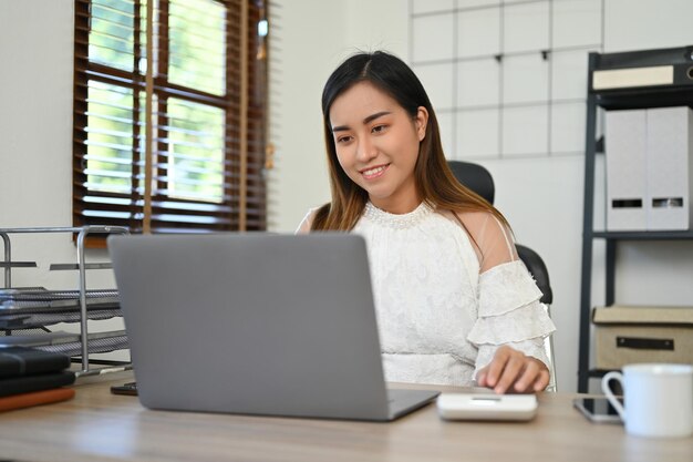 Mujer de negocios asiática que trabaja en su escritorio usando una computadora portátil para administrar sus tareas comerciales