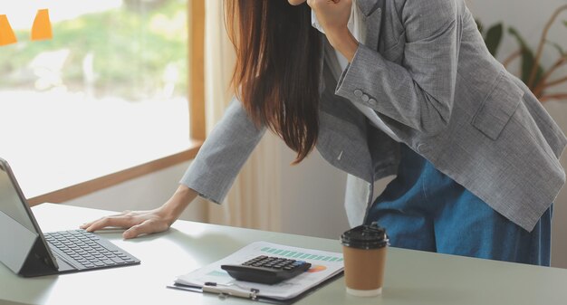 Mujer de negocios asiática que usa calculadora y computadora portátil para hacer finanzas matemáticas en un informe de impuestos de escritorio de oficina estadísticas contables y concepto de investigación analítica