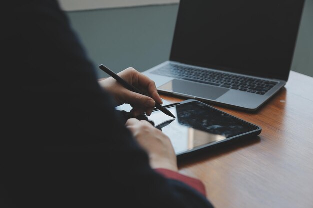 Mujer de negocios asiática que usa una computadora portátil y trabaja en la oficina con un documento de calculadora en el escritorio haciendo planificación analizando el concepto de análisis de finanzas de inversión del plan de negocios del informe financiero