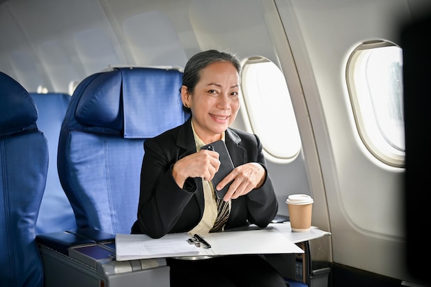 Una mujer de negocios asiática senior segura de sí misma que viaja en avión para su viaje de negocios