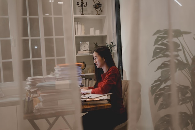 Mujer de negocios asiática trabajando duro hasta altas horas de la noche con muchos documentos en casa. Ocupado y agotado de trabajar horas extras por la noche.