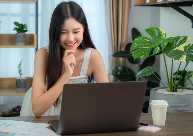 Foto mujer de negocios asiática trabajando en la oficina en casa en la mesa con un cuaderno de computadora y una taza de café