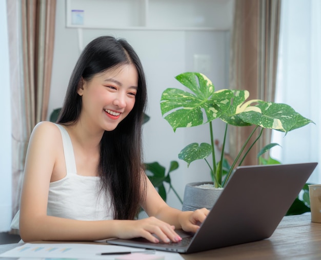 Foto mujer de negocios asiática trabajando en la oficina en casa en la mesa con un cuaderno de computadora y una taza de café