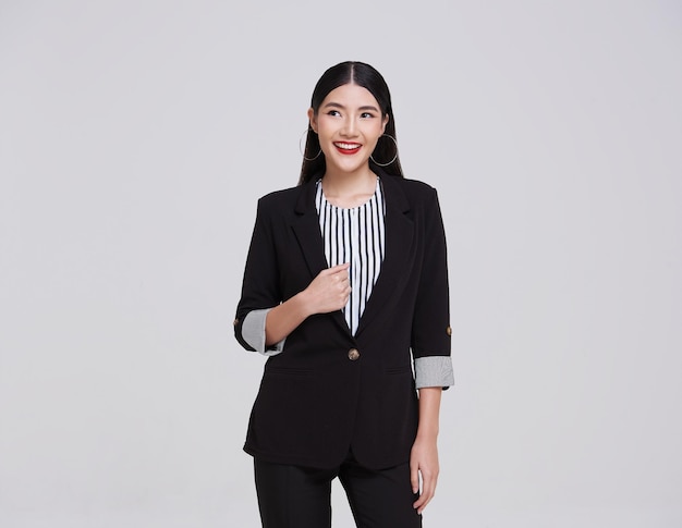 mujer de negocios asiática en traje de pie con mirando hacia arriba aislado en el fondo del espacio de copia gris