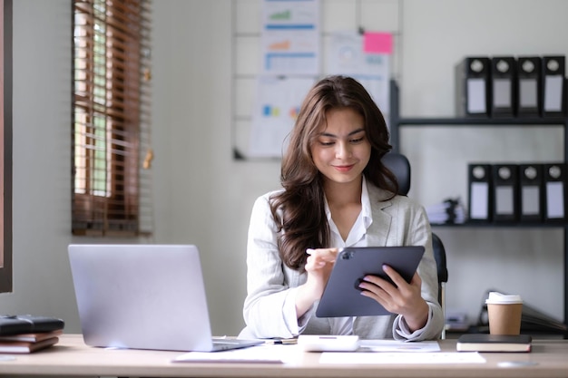 Mujer de negocios asiática usando calculadora y portátil para hacer finanzas matemáticas en un escritorio de oficina informe de impuestos estadísticas de contabilidad y concepto de investigación analítica