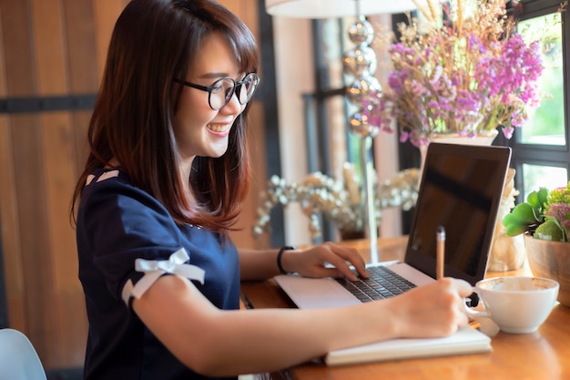 Mujer de negocios asiáticos trabajando con hacer una nota con un portátil y una computadora portátil