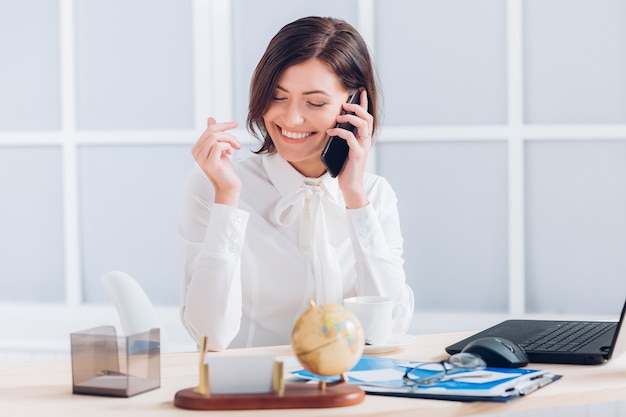 Mujer de negocios atractiva hablando por teléfono y trabajando en el escritorio en la oficina