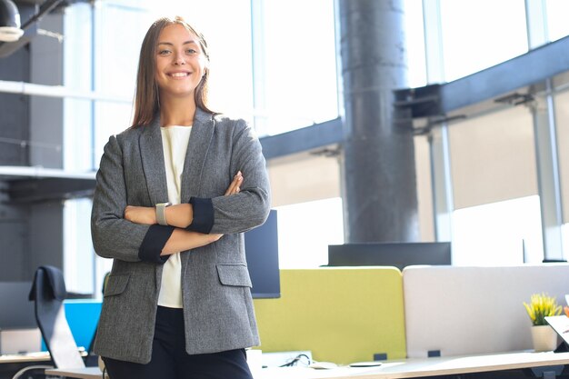 Mujer de negocios atractiva sonriendo mientras está de pie en la oficina.