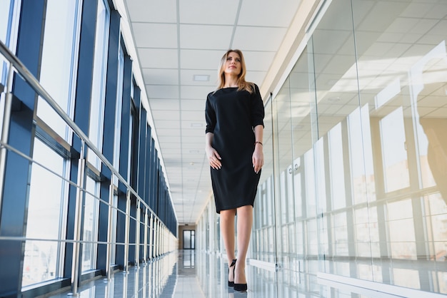 Mujer de negocios atractiva con un vestido negro en la oficina