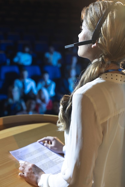 Foto mujer de negocios con auriculares dando una presentación en el auditorio