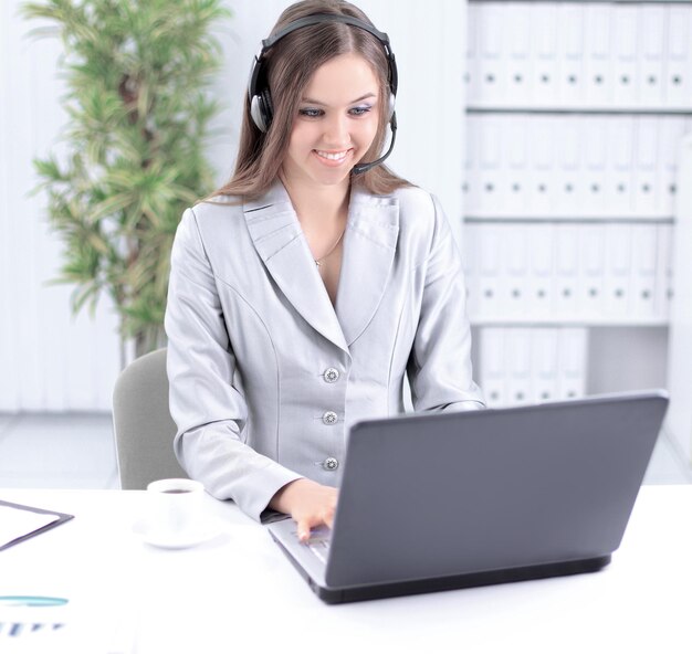 Mujer de negocios con auriculares trabajando en equipo portátil