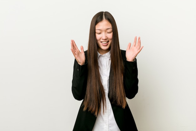 Mujer de negocios bastante china joven alegre que ríe mucho.