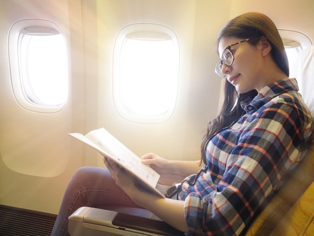 mujer de negocios bastante exitosa tomando el avión yendo a trabajar y leyendo la revista del avión buscando productos libres de impuestos para ir de compras.