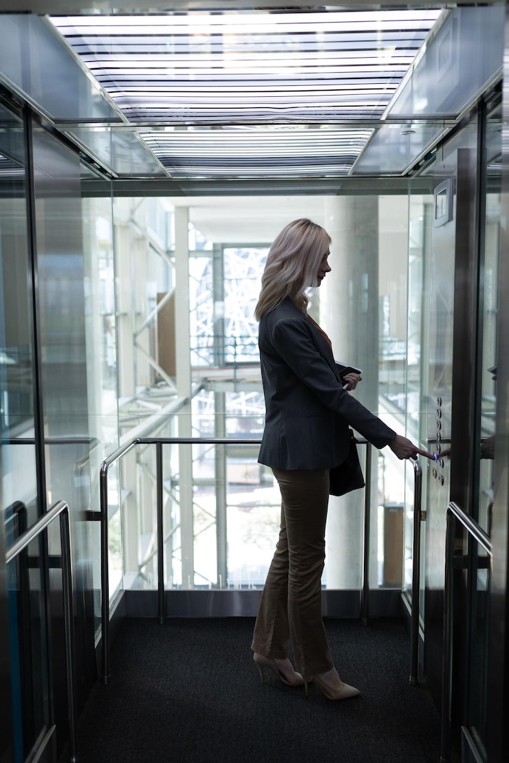 Foto mujer de negocios blanca rubia que usa el ascensor en la oficina