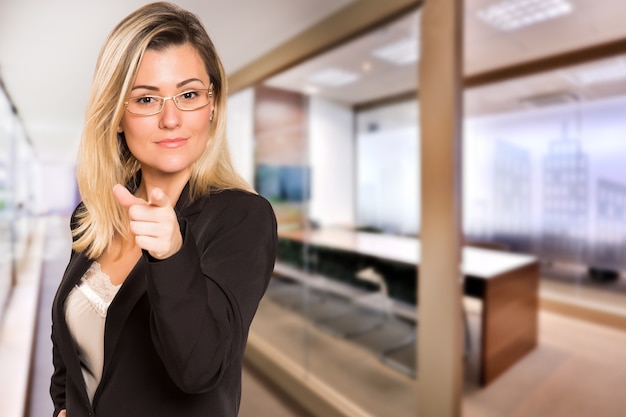 La mujer de negocios brasileña con tarjeta blanca en la mano en el espacio de la oficina desenfocada. Copie el espacio.