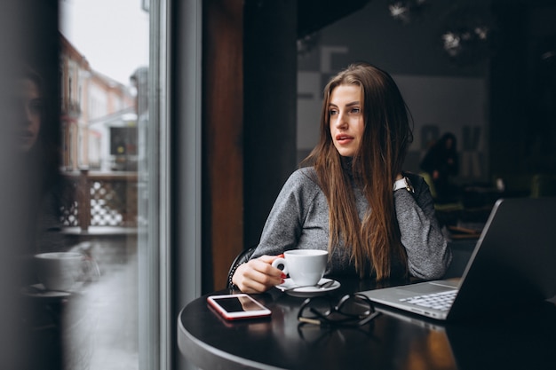 Mujer de negocios con café en una cafetería trabajando en computadora