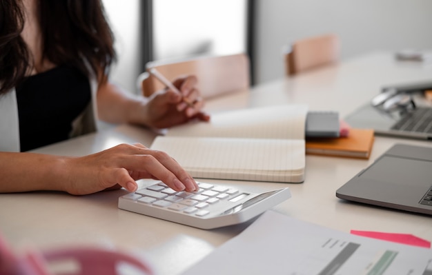 Mujer de negocios con calculadora contando haciendo notas en la oficina