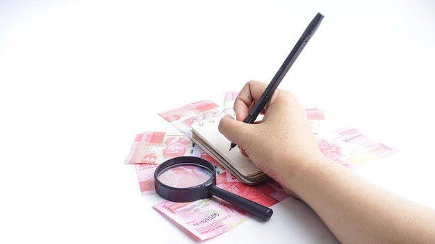 Mujer de negocios calcular con libro billetes de rupias indonesias sobre fondo blanco.