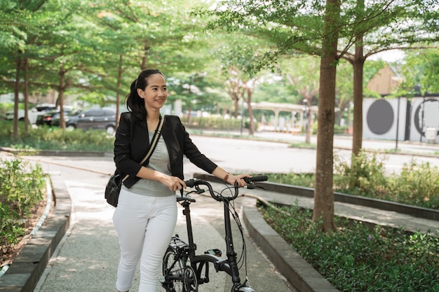 Mujer de negocios camina en su bicicleta plegable mientras recibe una llamada telefónica