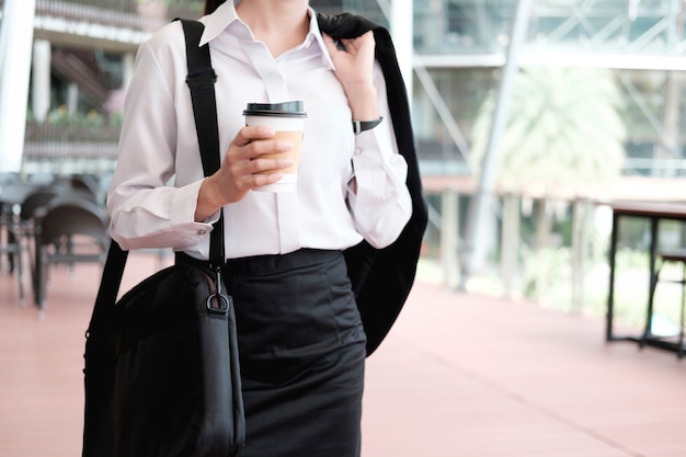 Mujer de negocios caminando bebiendo café.