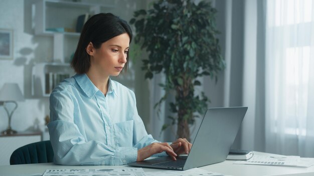 Una mujer de negocios con una camisa azul se sienta en un espacio de trabajo moderno