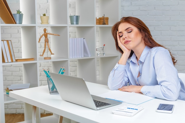 Mujer de negocios cansada hermosa que duerme en el trabajo