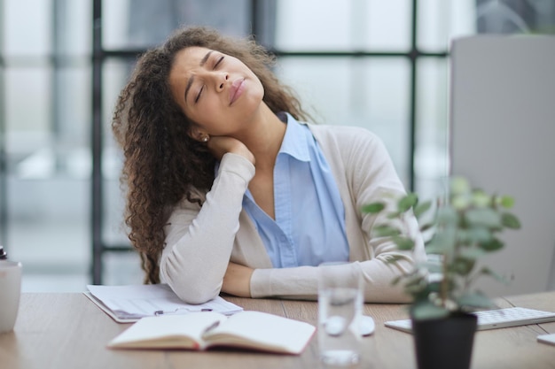 Mujer de negocios cansada sentada en el escritorio de la oficina y trabajando