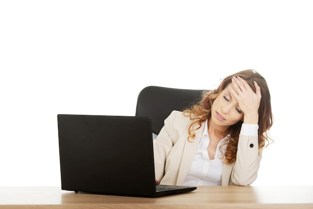 Mujer de negocios cansada usando una computadora portátil en el escritorio de la oficina