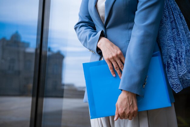 Mujer de negocios con carpeta en la mano cerca de un edificio de oficinas