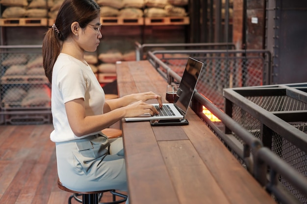 Mujer de negocios casual que usa un teléfono inteligente y una computadora portátil mujer independiente que escribe teclado computadora portátil en un café o tecnología de oficina moderna concepto digital en línea y de red