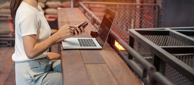 Mujer de negocios casual que usa un teléfono inteligente y una computadora portátil mujer independiente que escribe teclado computadora portátil en un café o tecnología de oficina moderna concepto digital en línea y de red